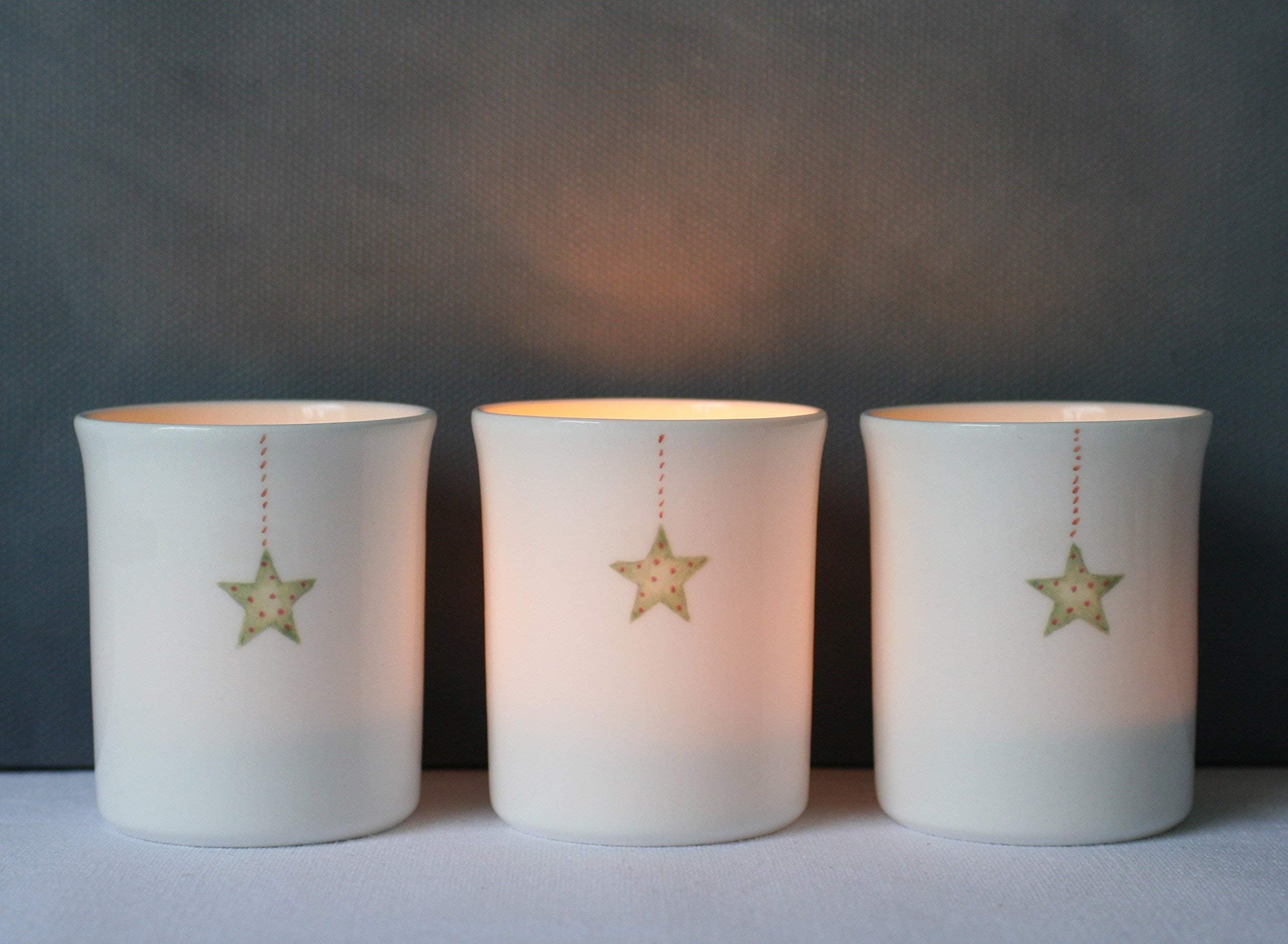 A set of three bone china tea light holders with little painted hanging stars